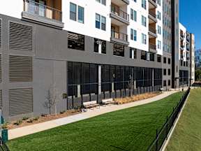 A modern apartment building with a grassy area in front.