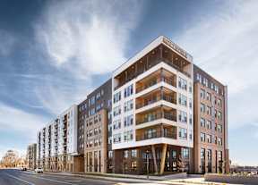 A modern multi-story building with the name "SUNSET HILLS" on the top.