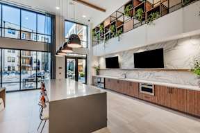 A modern kitchen with a large island and a TV mounted on the wall.