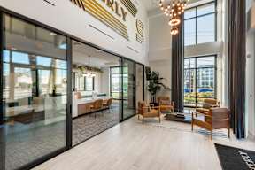 A modern waiting area with glass doors and wooden chairs.