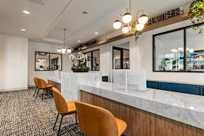 A reception area with a white counter and orange chairs.