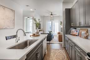 A modern kitchen with a large sink and a view of the living room.