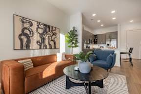 A living room with a brown couch and a large abstract painting on the wall.