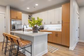 A kitchen with a white island and wooden chairs.