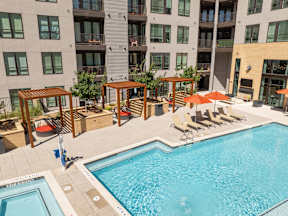 A large swimming pool with a wooden pergola and lounge chairs.