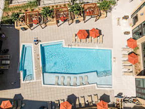 A large swimming pool surrounded by orange chairs and umbrellas.