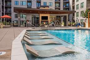 A large swimming pool with a water slide in front of a building.