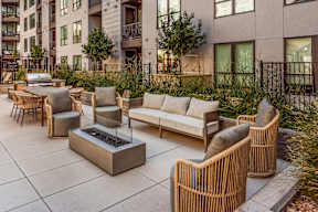 A patio with a fire pit and chairs.