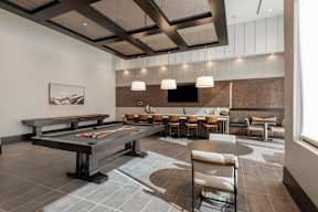 A billiard table is in the middle of a room with a bench and chairs.