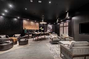 A modern living room with dark furniture and a flat screen TV mounted on the wall.