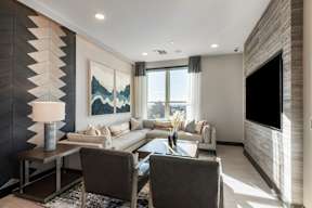 A modern living room with a grey sofa, a coffee table, and a large painting on the wall.