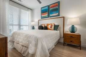 A bedroom with a white bed and a wooden nightstand.