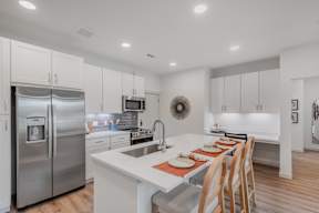A modern kitchen with a white countertop and stainless steel appliances.
