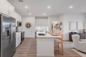A modern kitchen with a stainless steel refrigerator and wooden flooring.