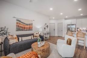 A living room with a grey couch, a white chair, and a wooden coffee table.