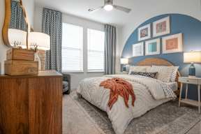 A bedroom with a bed, a wooden dresser, and a ceiling fan.