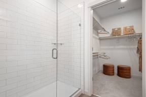 A white tiled bathroom with a walk in shower and a small closet.