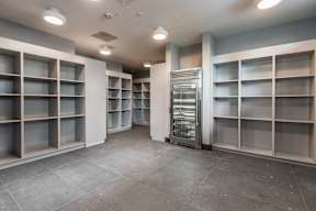 A large, empty storage room with grey shelving units and a freezer.