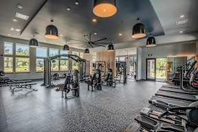 A spacious gym with a variety of equipment and a ceiling fan.