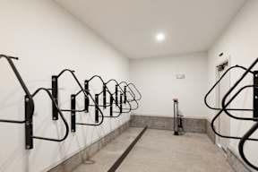 A row of black handrails on a white wall.