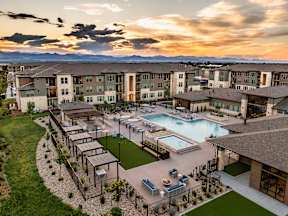 A sunset view of a resort with a pool and a patio.