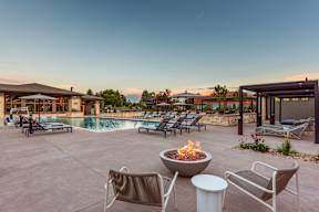 A fire pit sits in the middle of a patio with chairs and a table.