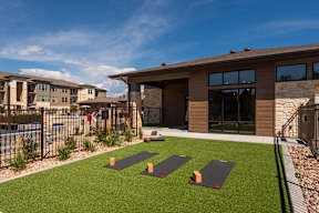 A yoga mat is placed on a green lawn in front of a house.
