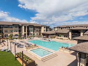 A large swimming pool surrounded by a grassy area and a building in the background.