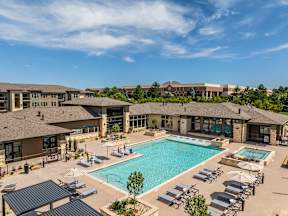 A large outdoor swimming pool surrounded by sun loungers and a building in the background.