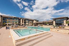 A swimming pool in front of a building with a clear blue sky.