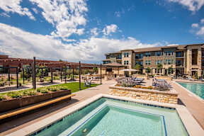 A pool surrounded by a stone wall and chairs.