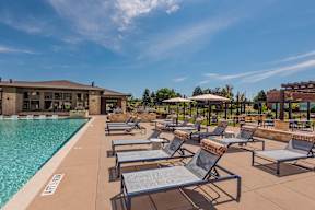 A poolside area with sun loungers and a building in the background.