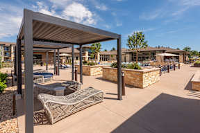 A modern outdoor seating area with a stone wall and a metal structure.