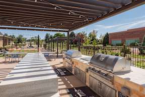 A covered outdoor seating area with grills and tables.