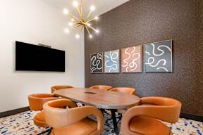 A conference room with a round table surrounded by orange chairs.