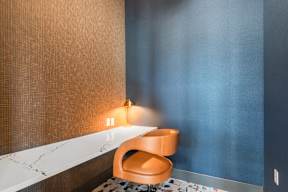 A chair sits in front of a wall with a lamp on it.