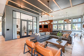 A modern living room with a grey sofa, orange chairs, and a wooden coffee table.