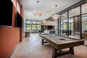 A pool table is in the middle of a room with a television on the wall.