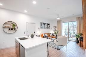A modern kitchen with a white countertop and a dining area with a couch and chairs.