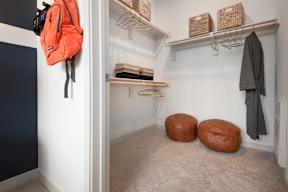 A small closet with a hanging coat and a bag hanging on the door.