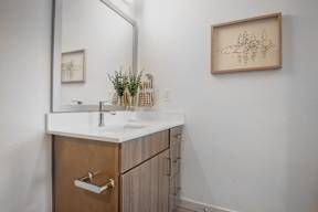 A bathroom with a brown cabinet and a framed drawing on the wall.