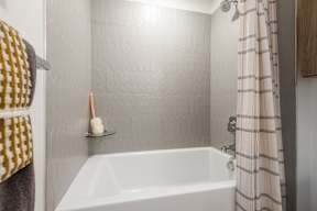 A white bathtub with a shower curtain and a towel hanging on the wall.