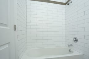 Bathtub in bathroom with white tile walls