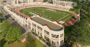 A large stadium with a track and field is surrounded by trees.