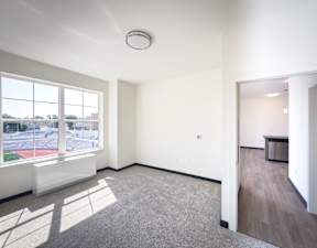 A large empty room with a window overlooking a parking lot.