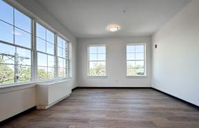 A large empty room with wooden floors and large windows.