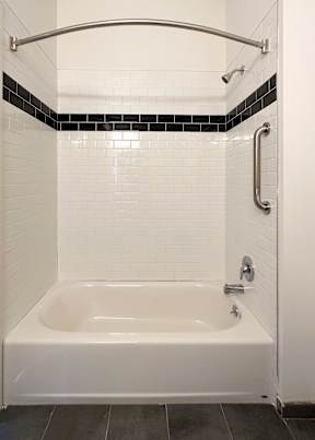 A white bathtub with a black and white tile wall.