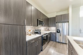 Updated Kitchen With Black Appliances and wooden cabinets at Residences at 3000 Bardin Road, Grand Prairie, Texas