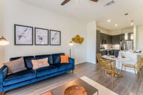 Living room with a blue couch and kitchen with wood flooring at Residences at 3000 Bardin Road, Texas