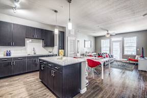 a kitchen and living room with dark cabinets and a white table with red chairs at Republic at Alamo Heights, San Antonio, TX